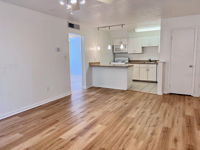 kitchen with light wood-style floors, white cabinets, a sink, a textured ceiling, and white appliances