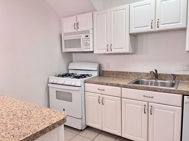 kitchen with white appliances, white cabinets, a sink, and light tile patterned floors