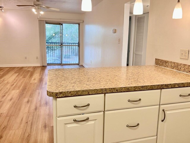 kitchen featuring hanging light fixtures, light wood-style floors, ceiling fan, and white cabinets