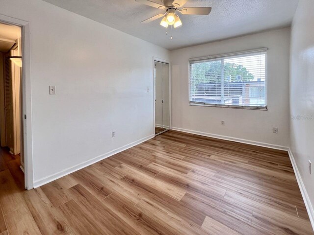 spare room featuring a textured ceiling, wood finished floors, a ceiling fan, and baseboards