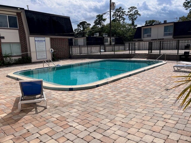 community pool with a patio and fence