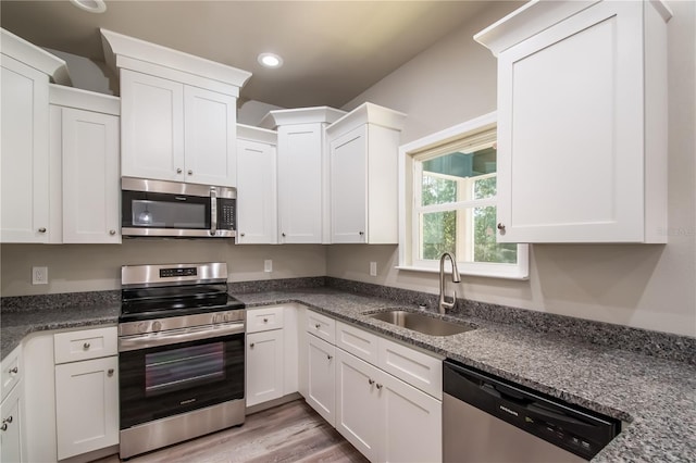 kitchen featuring stainless steel appliances, white cabinetry, sink, and dark stone counters