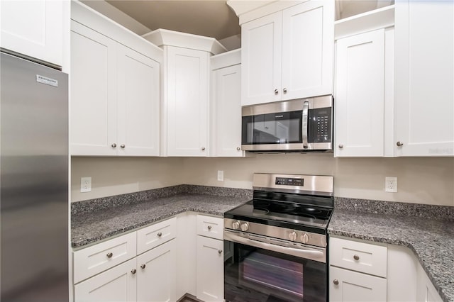 kitchen with dark stone counters, appliances with stainless steel finishes, and white cabinets