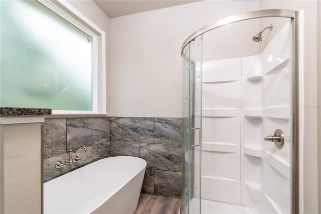 bathroom with tile walls, hardwood / wood-style floors, and separate shower and tub