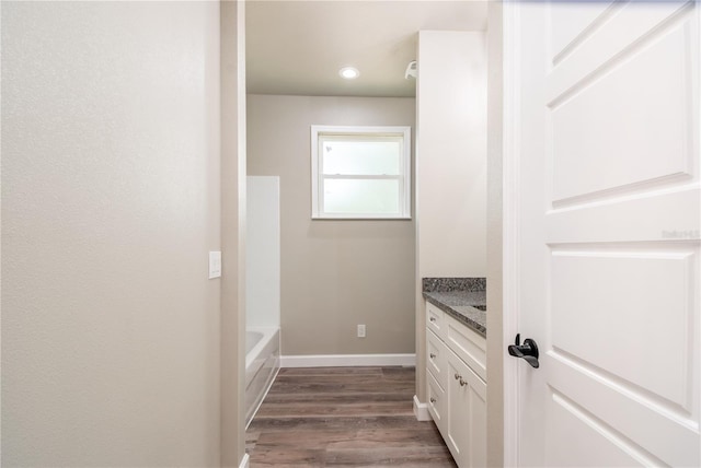 full bathroom featuring vanity, wood finished floors, baseboards, a bathtub, and recessed lighting