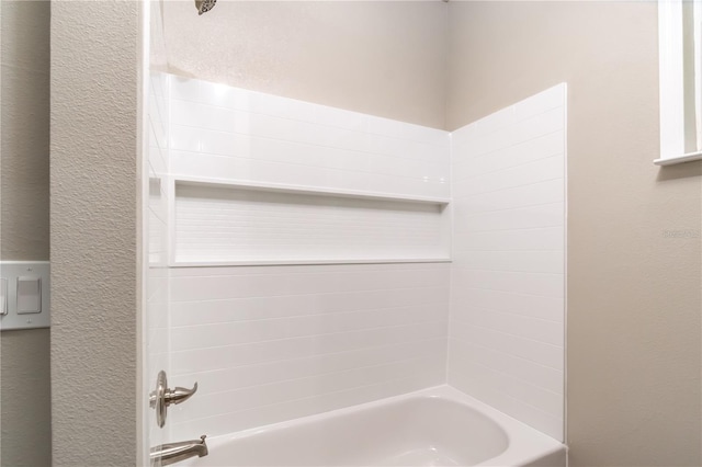 full bathroom with a textured wall and bathtub / shower combination