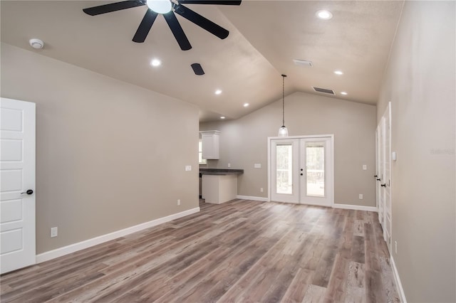 unfurnished living room featuring ceiling fan, french doors, light hardwood / wood-style flooring, and lofted ceiling