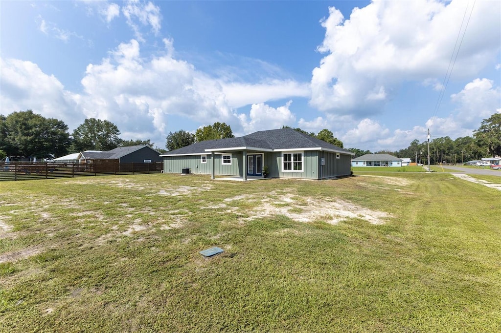 back of house featuring fence and a lawn