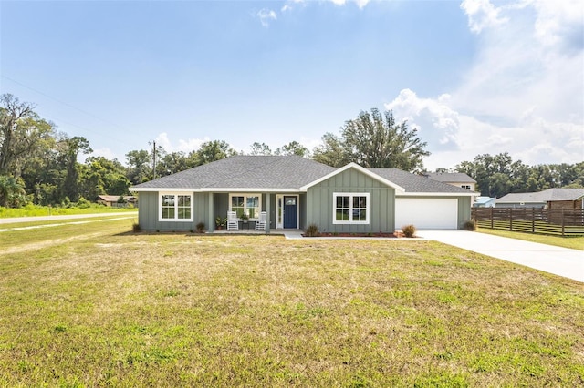 single story home featuring a front lawn, covered porch, and a garage