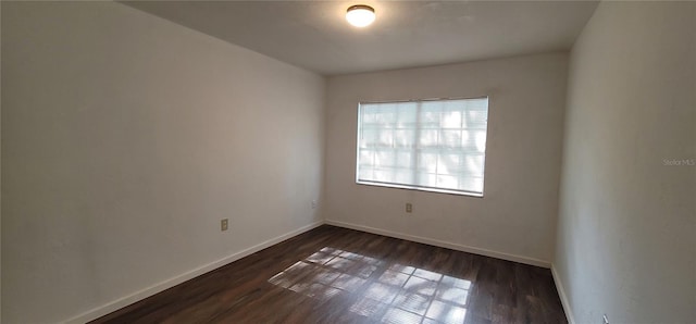 empty room featuring dark wood-style floors and baseboards