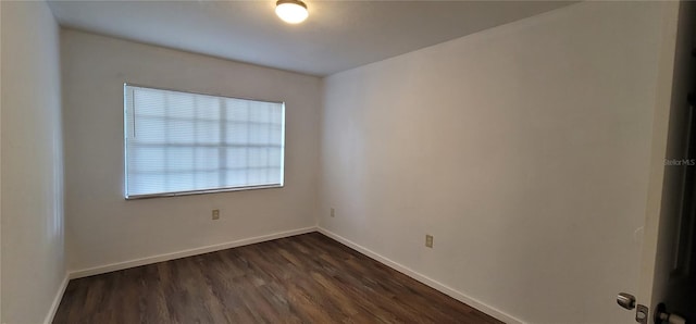 empty room with dark wood-type flooring and baseboards