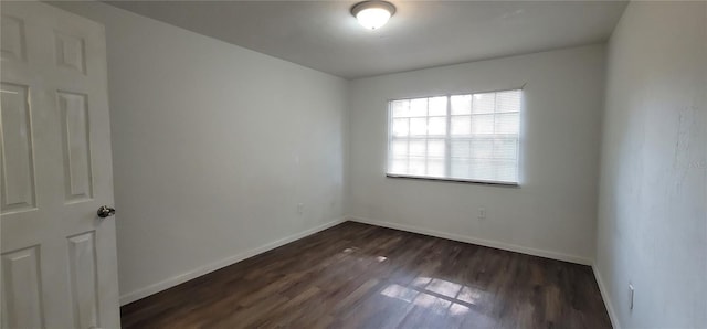 spare room featuring dark wood finished floors and baseboards