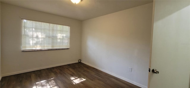 unfurnished room featuring dark wood-type flooring and baseboards