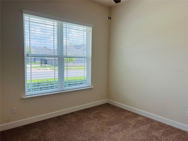 empty room with carpet flooring, a ceiling fan, and baseboards