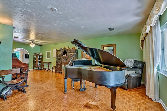 miscellaneous room with ceiling fan, light parquet floors, and a textured ceiling