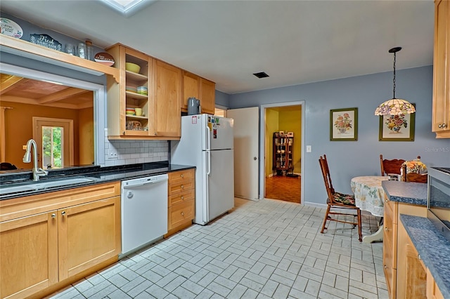 kitchen with pendant lighting, backsplash, sink, and white appliances