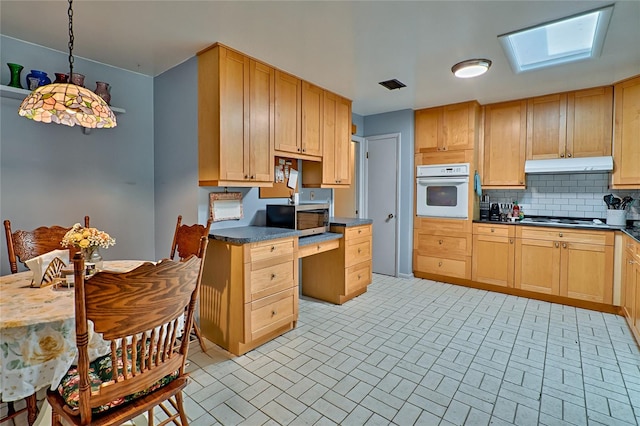 kitchen with appliances with stainless steel finishes, hanging light fixtures, light brown cabinets, and tasteful backsplash