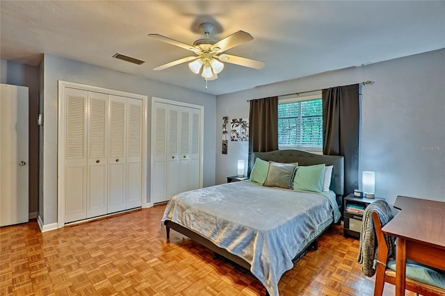 bedroom with ceiling fan, multiple closets, and light parquet flooring