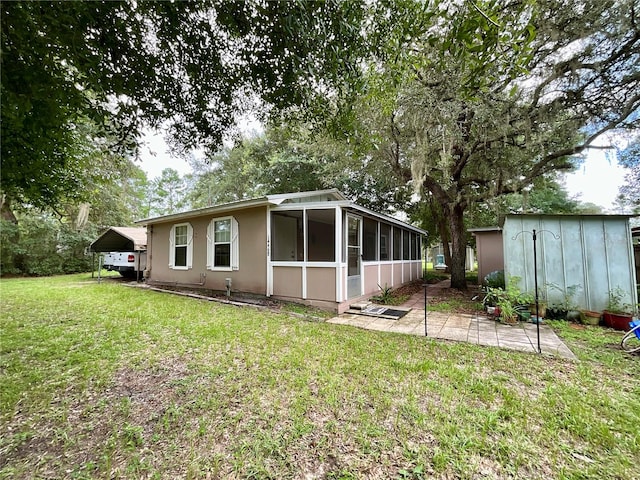 rear view of house with a lawn, a sunroom, and a shed