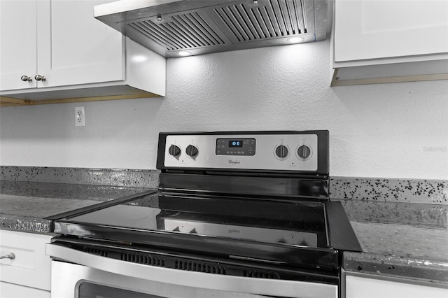 kitchen featuring custom range hood, dark stone countertops, electric range, and white cabinetry