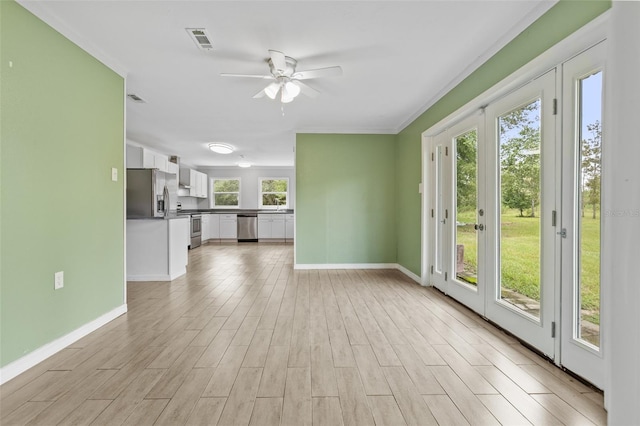 unfurnished living room with a healthy amount of sunlight, ceiling fan, french doors, and light hardwood / wood-style floors