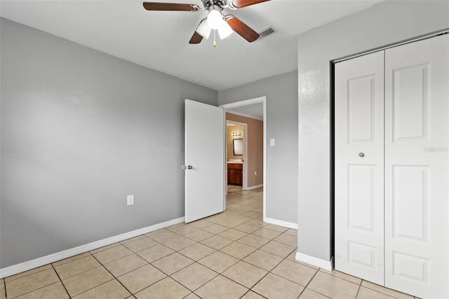 unfurnished bedroom with light tile patterned floors, ceiling fan, and a closet