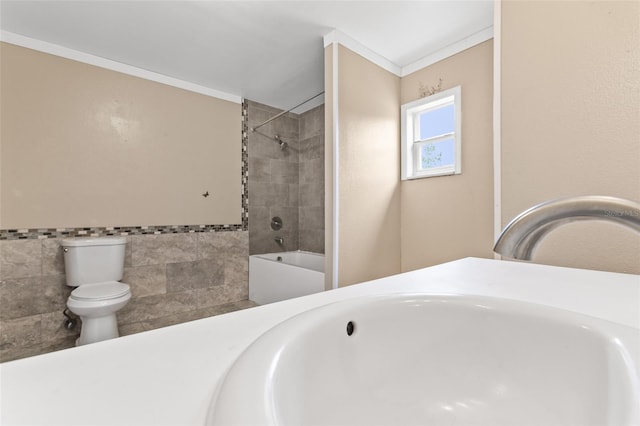 bathroom with tiled shower / bath combo, tile walls, toilet, and crown molding