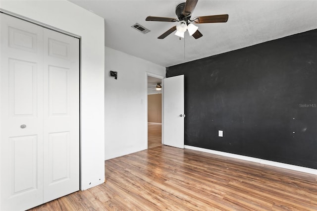 unfurnished bedroom featuring hardwood / wood-style floors, ceiling fan, and a closet