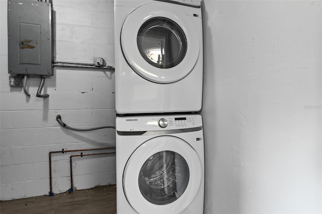 laundry room with stacked washing maching and dryer, electric panel, and hardwood / wood-style floors