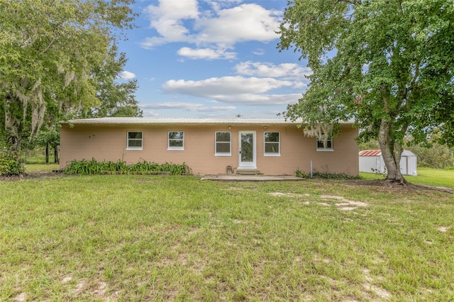 rear view of property featuring a lawn and a storage shed