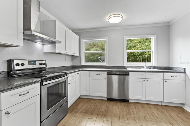 kitchen featuring wall chimney range hood, stainless steel appliances, light hardwood / wood-style floors, and sink