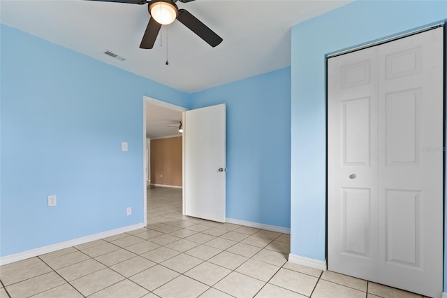 unfurnished bedroom featuring ceiling fan, a closet, and light tile patterned flooring