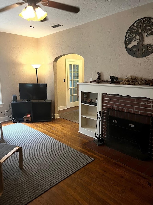 living room featuring ceiling fan, a textured ceiling, and wood-type flooring