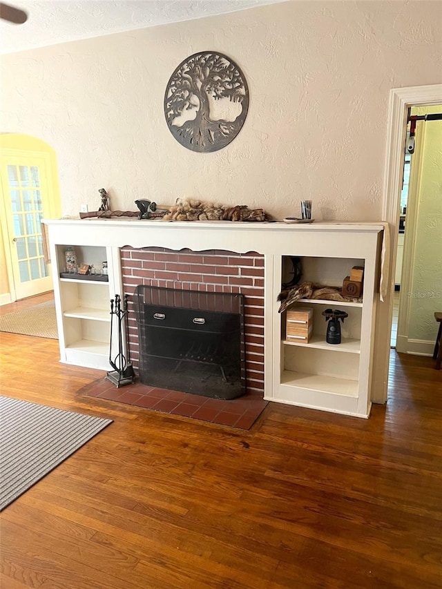 interior space with wood-type flooring, a textured ceiling, and a brick fireplace