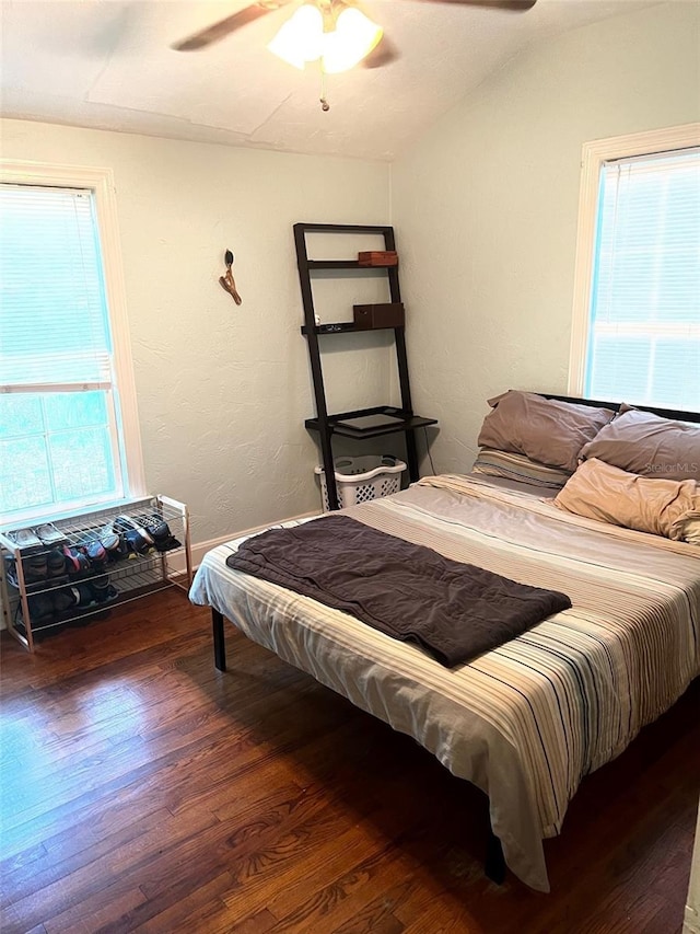 bedroom with ceiling fan, lofted ceiling, multiple windows, and hardwood / wood-style flooring