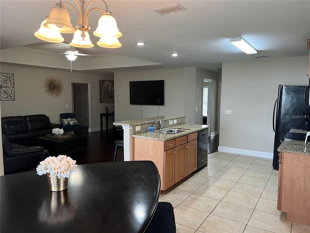 kitchen featuring light tile patterned flooring, sink, a kitchen island with sink, hanging light fixtures, and black appliances