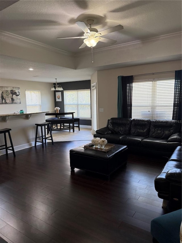 living room with a textured ceiling, ornamental molding, and dark wood-style flooring