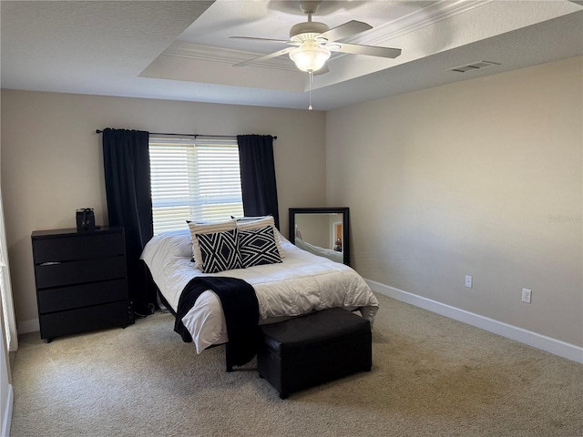 bedroom featuring visible vents, baseboards, a ceiling fan, light colored carpet, and a tray ceiling