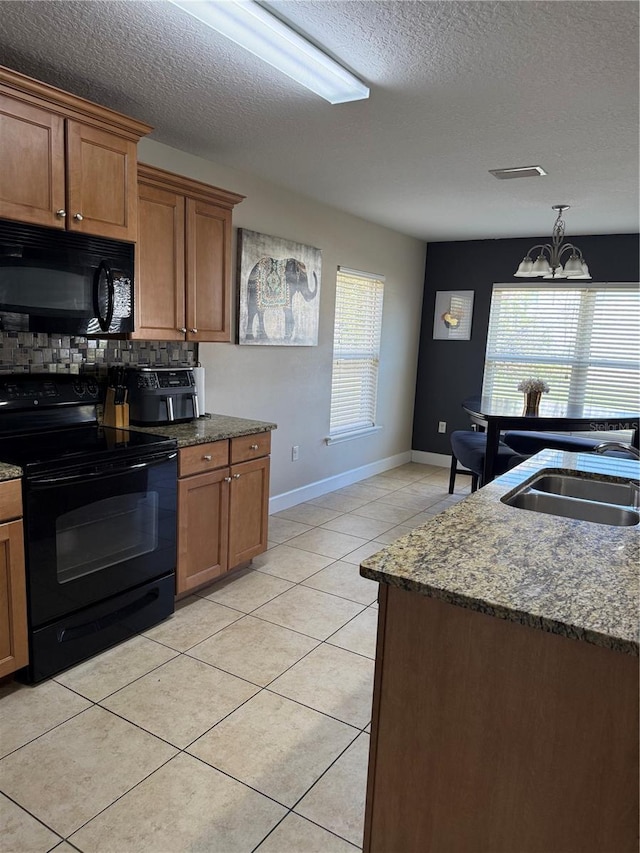 kitchen with black appliances, brown cabinetry, a sink, and light tile patterned flooring