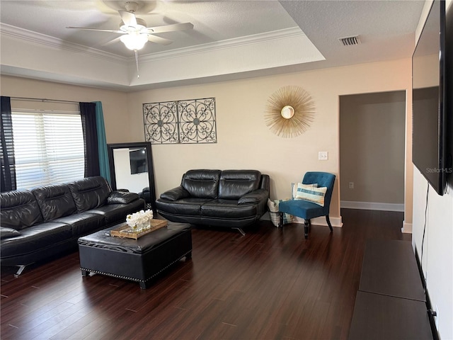 living room with a tray ceiling, visible vents, ceiling fan, and wood finished floors