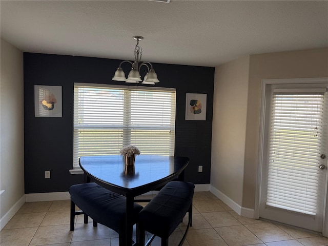 dining space featuring light tile patterned floors, a textured ceiling, baseboards, and an inviting chandelier