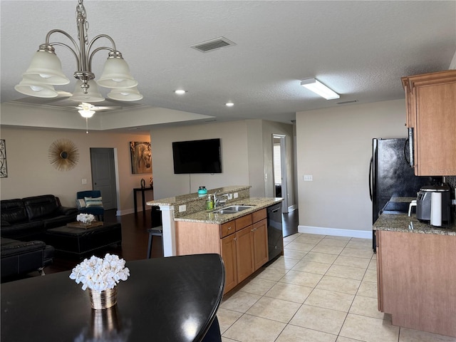 kitchen featuring black dishwasher, brown cabinets, open floor plan, light tile patterned flooring, and a sink