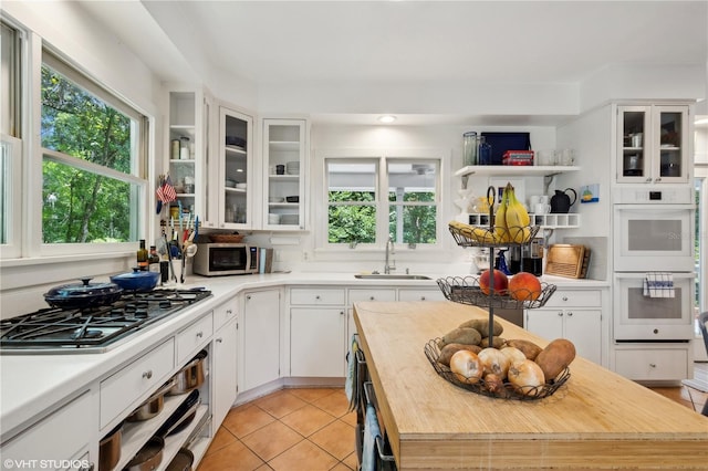 kitchen with stainless steel appliances, white cabinetry, plenty of natural light, and sink