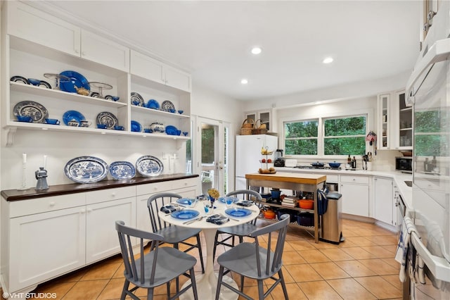 kitchen featuring white fridge, light tile patterned floors, and white cabinets