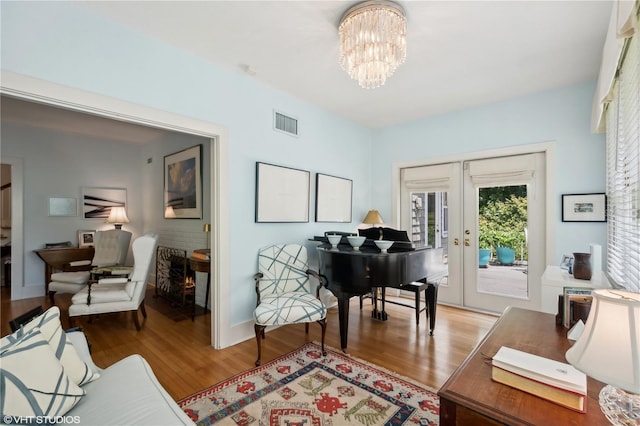 sitting room featuring wood-type flooring, an inviting chandelier, and french doors