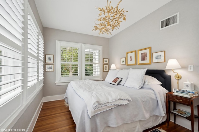 bedroom with an inviting chandelier and dark hardwood / wood-style flooring