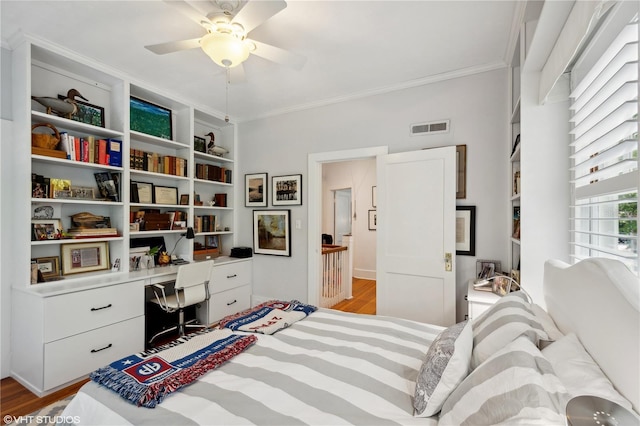 bedroom featuring crown molding, built in desk, ceiling fan, and light hardwood / wood-style floors