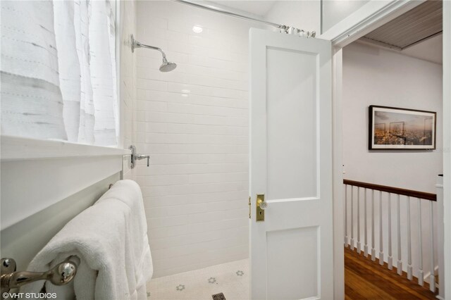 bathroom featuring wood-type flooring and a tile shower