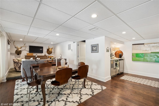 dining space with dark hardwood / wood-style floors and a drop ceiling