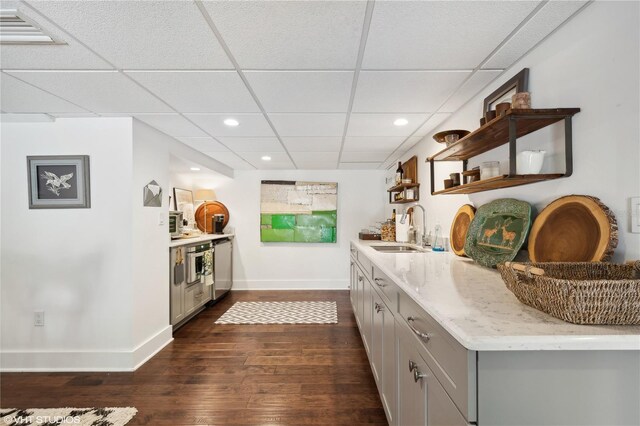 bar with gray cabinets, sink, light stone counters, and dark hardwood / wood-style floors